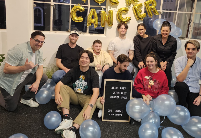 Large group photo of the team at a milestone celebration